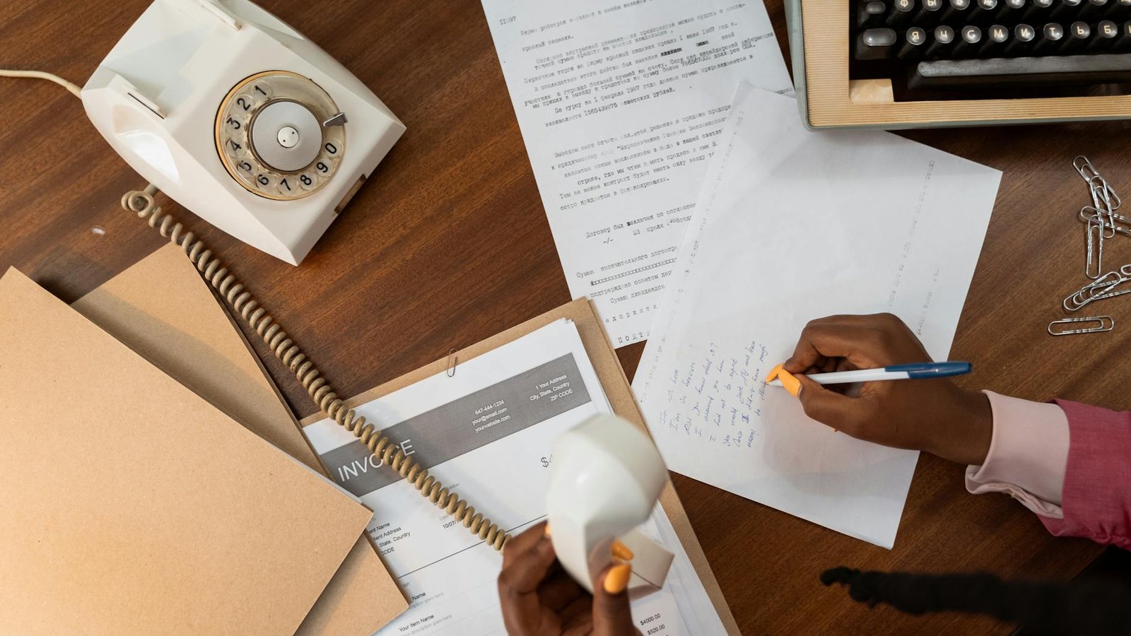 Hands writing a response to an official typed letter on a wooden desk